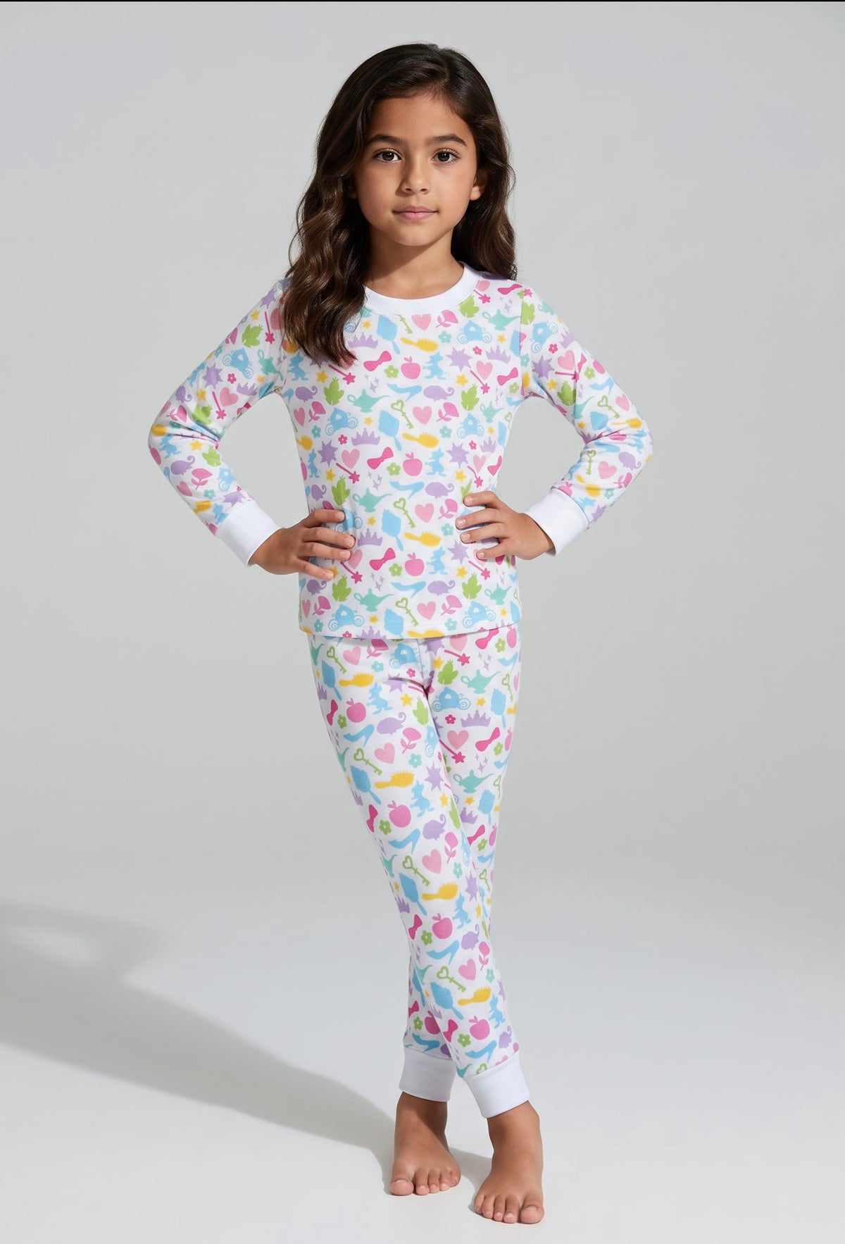 Girl modeling Polly & Pearl pastel princess bamboo pajamas with colorful crowns, hearts and white cuffs