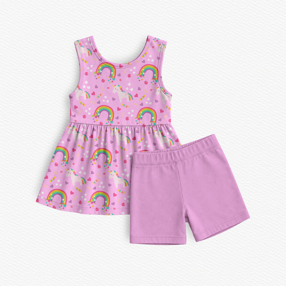 A girl's two-piece bamboo viscose outfit set featuring a pink sleeveless peplum top dress with a rainbow and heart pattern, paired with pink coordinating biker shorts, laid flat on a white textured background.