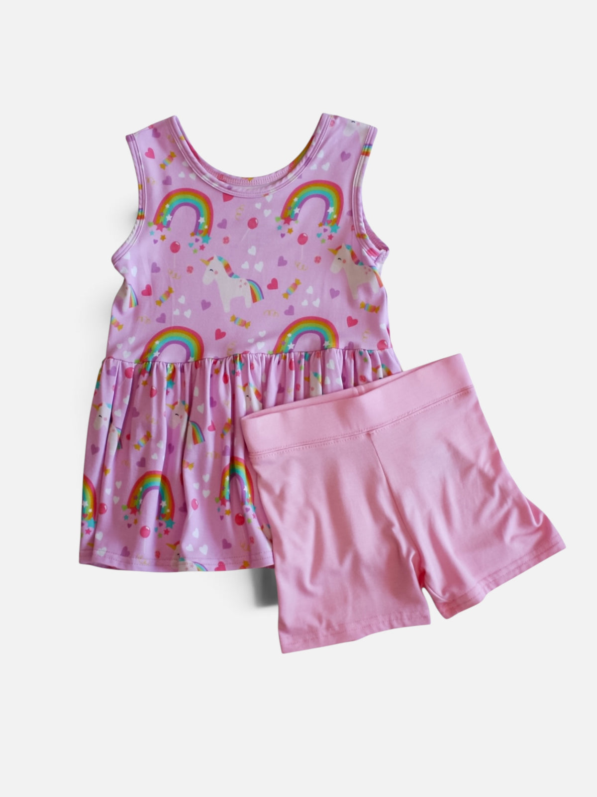  Girl's two-piece bamboo viscose clothing set featuring a sleeveless pink dress with a rainbow and unicorn print, paired with solid pink shorts, displayed on a light gray background.